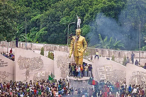 Protesters climbing a public monument while celebrating the resignation of Sheikh Hasina from the prime ministerial post in August 2024