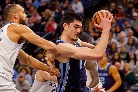 NBA 2024-25: Grizzlies center Zach Edey grabs a rebound as Timberwolves center Rudy Gobert defends
