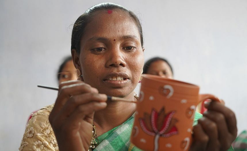 Adivasi artisan doing traditional Sohrai Art on a Terracotta Coffee Mug