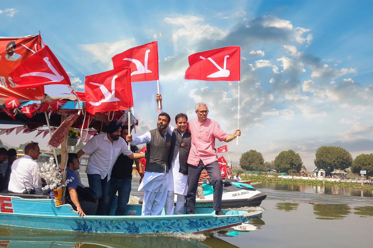 PTI : National Conference Vice President Omar Abdullah holds the party flag as he takes a 'shikara' ride during a rally for Jammu & Kashmir Assembly elections