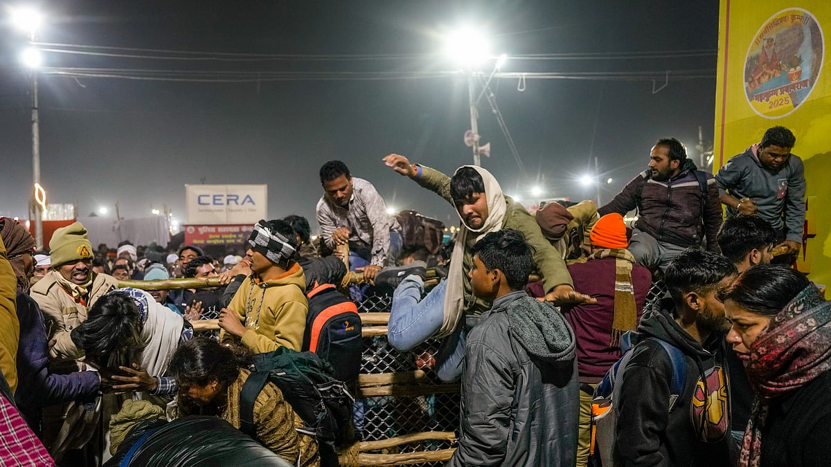 PTI/Ravi Choudhary : Devotees climb a barrier amid restrictions after a stampede-like situation during the ongoing 'Maha Kumbh Mela' festival, in Prayagraj, Wednesday, Jan. 29, 2025. 