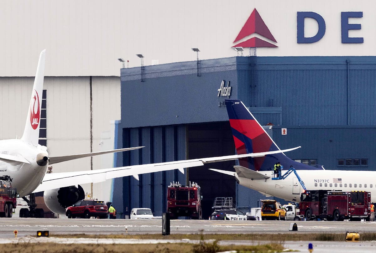 Ellen M. Banner/The Seattle Times via AP : Workers on a lift check the area where the wing of a Japan Airlines jet went into the tail of a Delta Air Lines jet at the south end of a runway at Seattle-Tacoma International Airport on Wednesday, Feb. 5, 2025.