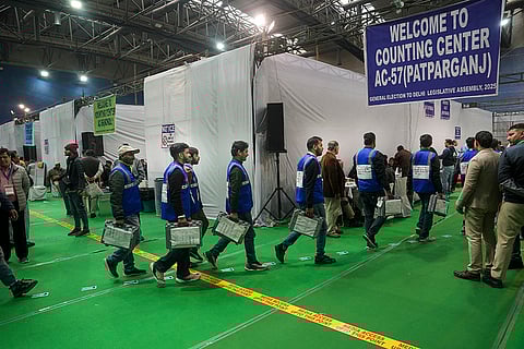 Poll officials carrying EVMs enter the Patparganj counting centre