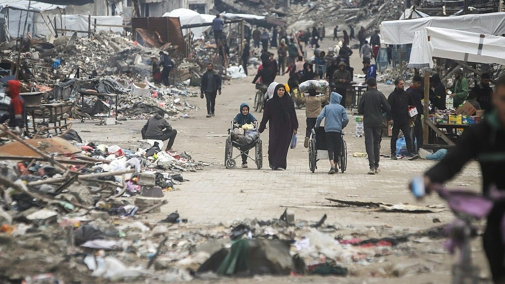 AP/JEHAD ALSHRAFI : Pedestrians walk along a road lined with few stands selling goods, amid widespread destruction caused by the Israeli military's ground and air offensive in Gaza City's Jabaliya refugee camp, Friday, Feb. 7, 2025. 