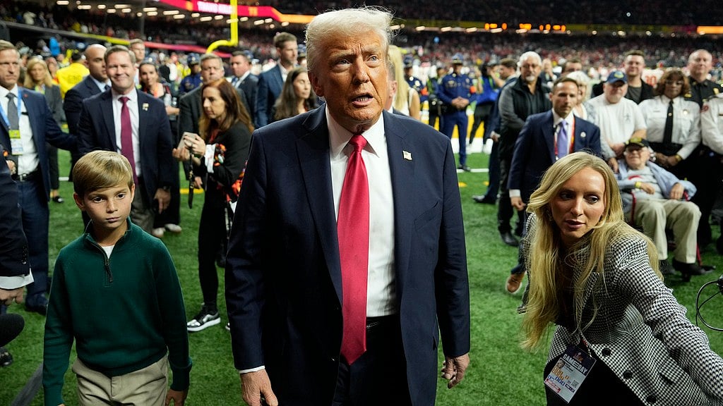AP : USA president Donald Trump with his grandson Theodore, left, walks on the field before the start of the NFL Super Bowl game.