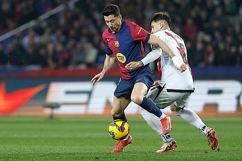 La Liga 2024-25: Rayo's Andrei Ratiu, right, challenges for the ball with Barcelona's Robert Lewandowski