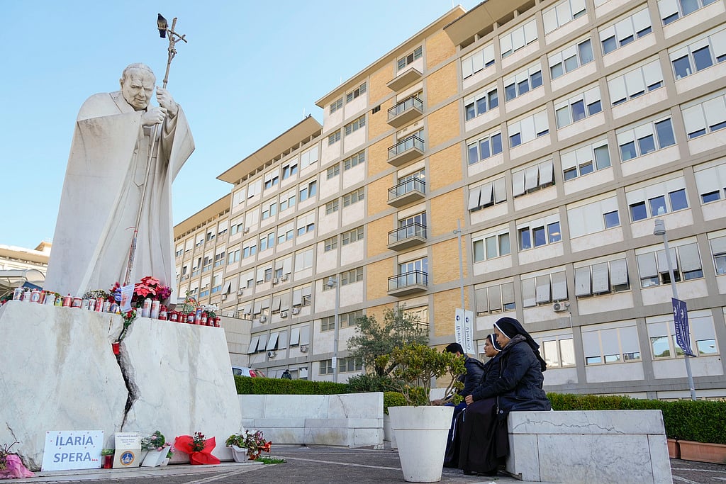 | Photo: AP : Nuns pray in front of the statue of late Pope John II outside the Agostino Gemelli Polyclinic where Pope Francis is battling pneumonia, in Rome.