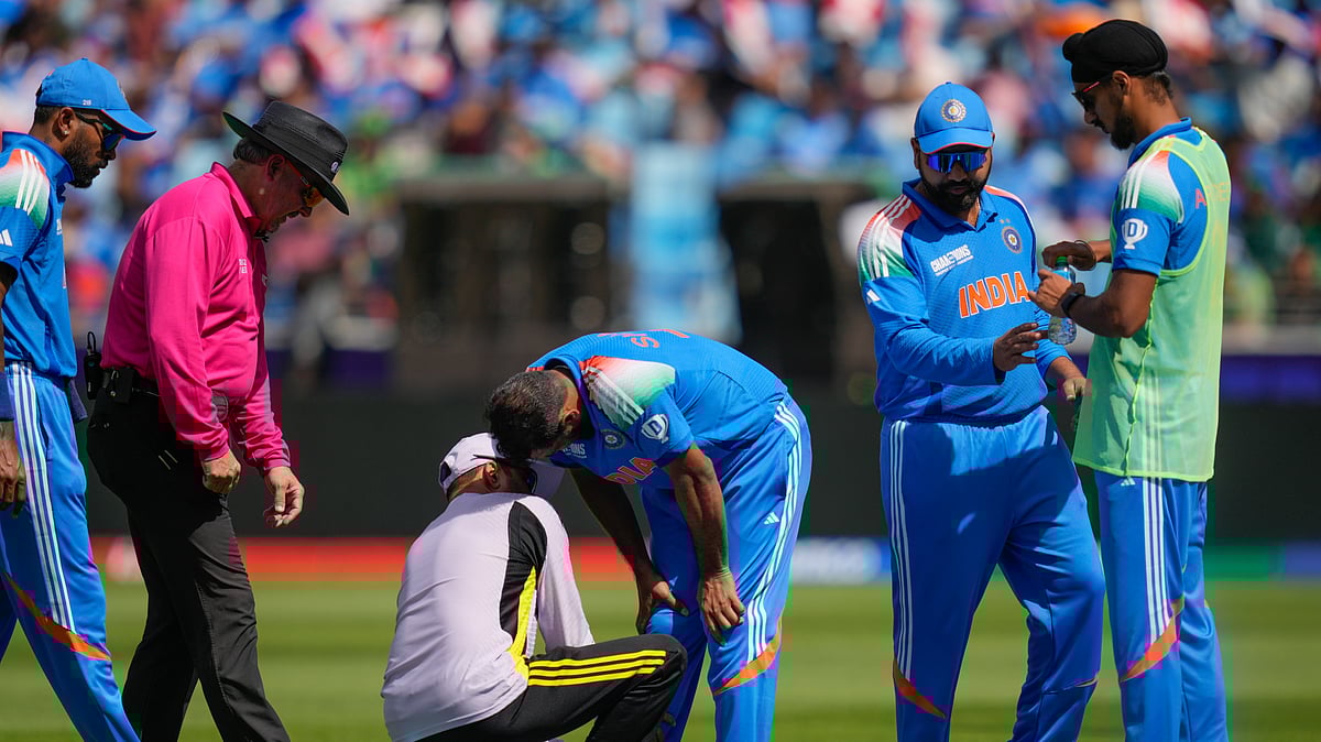 AP Photo/Altaf Qadri : India's Mohammed Shami, centre, is attended by the team physio during the ICC Champions Trophy cricket match between India and Pakistan at Dubai International Cricket Stadium.