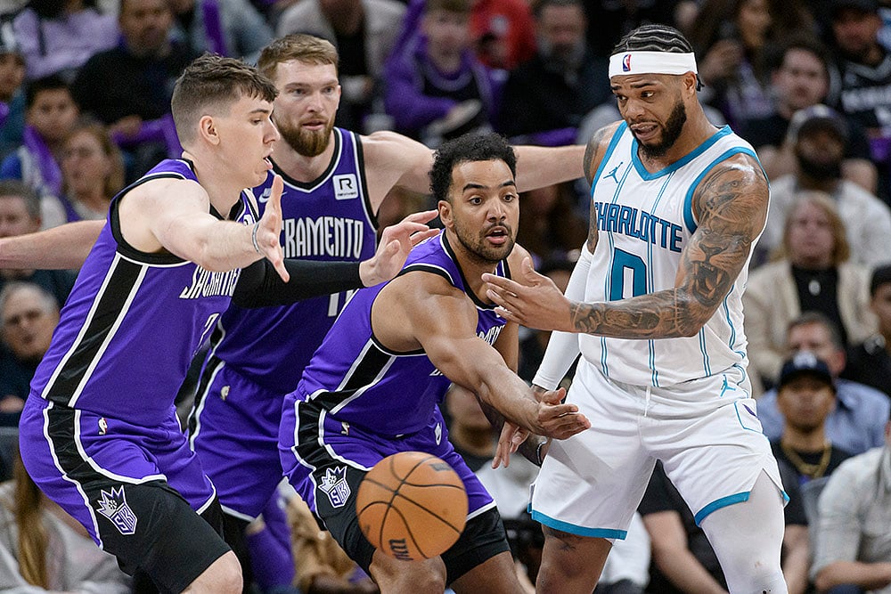 | Photo: AP/Randall Benton : NBA 2024-25: Hornets forward Miles Bridges (0) is guarded by Kings forward Jake LaRavia, Domantas Sabonis, and Trey Lyles