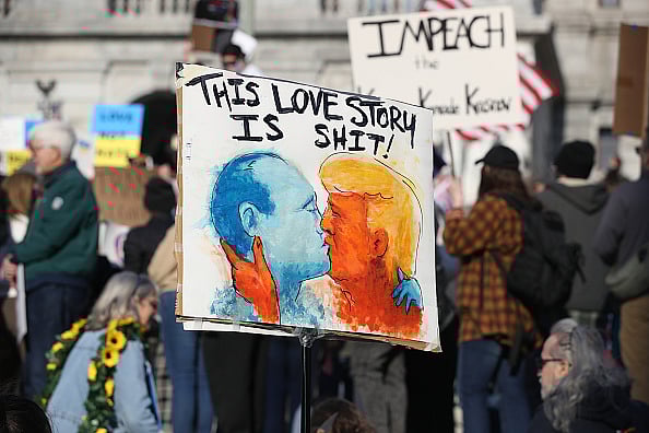 Getty Images : Protester holds a placard depicting Donald Trump and Vladimir Putin kissing during an anti-Trump demonstration 