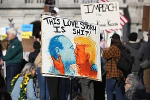 Getty Images : Protester holds a placard depicting Donald Trump and Vladimir Putin kissing during an anti-Trump demonstration
