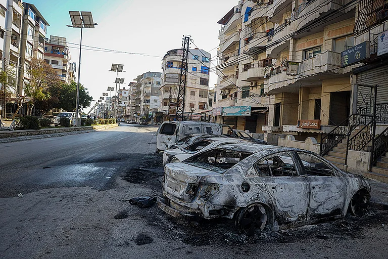 Syria Clashes: Burnt cars remain in the middle of a street - | Photo: AP/Omar Albam