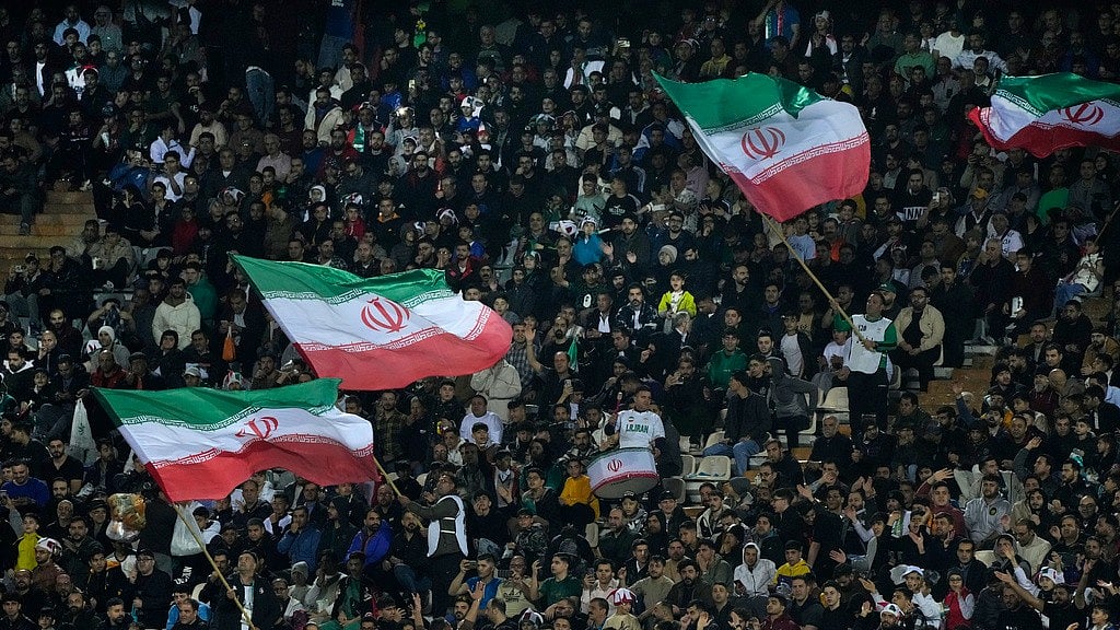 AP : Iranian spectators wave their country's flags as they follow Iran and UAE.