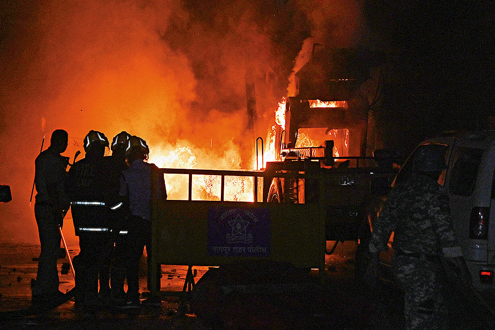 | Photo: AP : Tense Nights: Policemen watch vehicles being torched in violence-hit area of Nagpur
