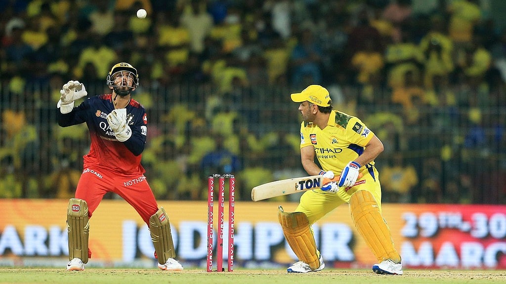 AP/R. Parthibhan : Royal Challengers Bengaluru's Jitesh Sharma, left, collects the ball as Chennai Super Kings' Mahendra Singh Dhoni bats during the Indian Premier League.