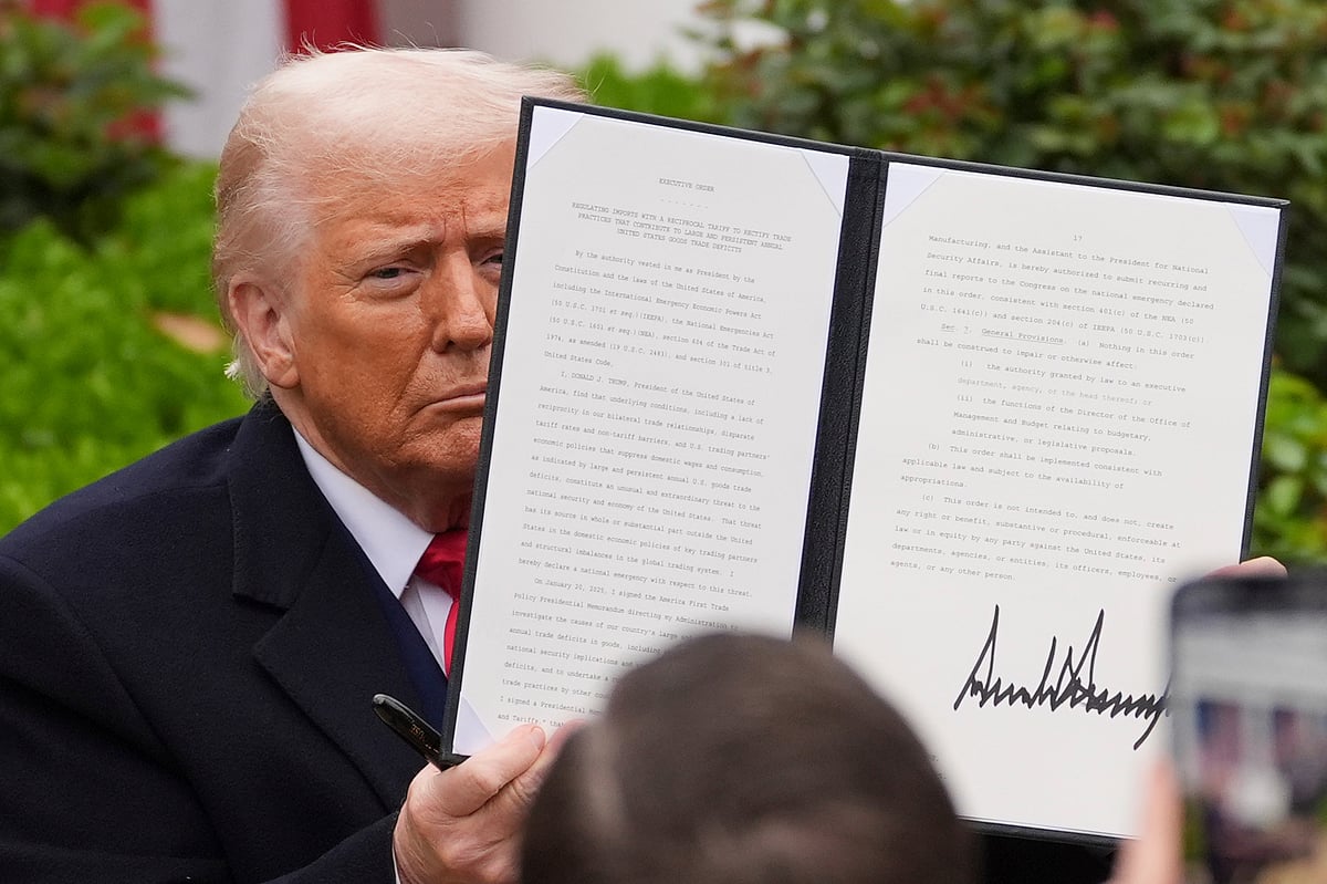 AP Photo : President Donald Trump holds a signed executive order to announce new tariffs in the White House.