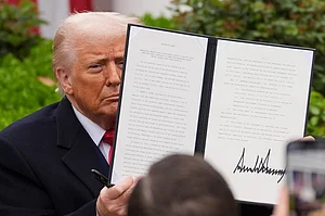 AP Photo : President Donald Trump holds a signed executive order to announce new tariffs in the White House.