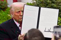 AP Photo : President Donald Trump holds a signed executive order to announce new tariffs in the White House.