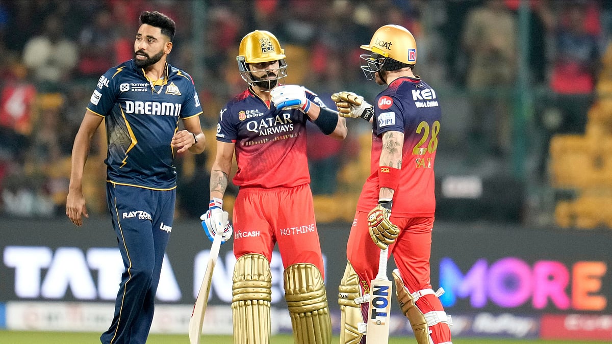 Royal Challengers Bengaluru's Virat Kohli, center, touches gloves with batting partner Phil Salt as Gujarat Titans' Mohammed Siraj walks on during the Indian Premier League cricket match between Gujarat Titans and Royal Challengers Bengaluru at Chinnaswamy Stadium in Bengaluru, India, Wednesday, April 2, 2025.  - (AP Photo/Aijaz Rahi)