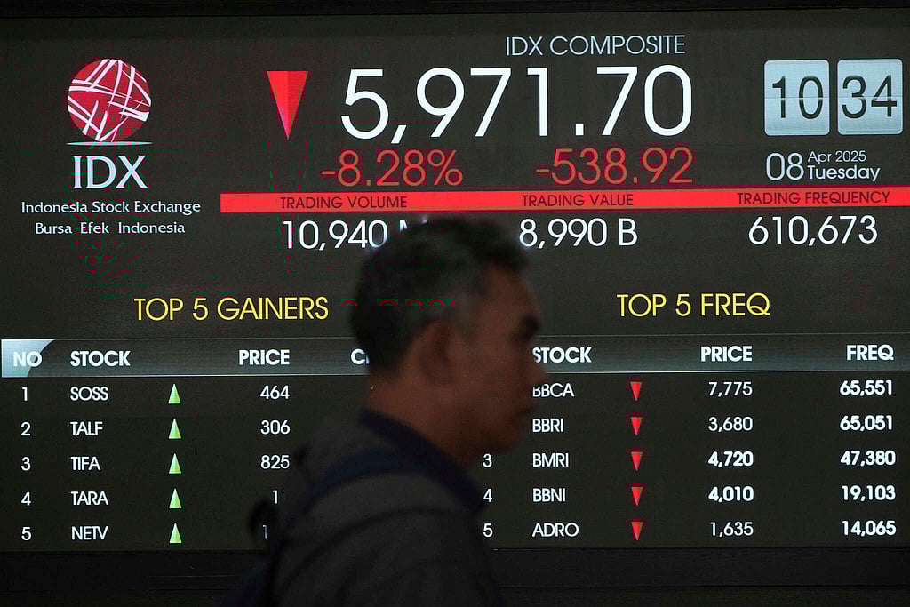| Photo: AP : A man walks past an electronic board displaying stock prices at the Indonesia Stock Exchange on Tuesday