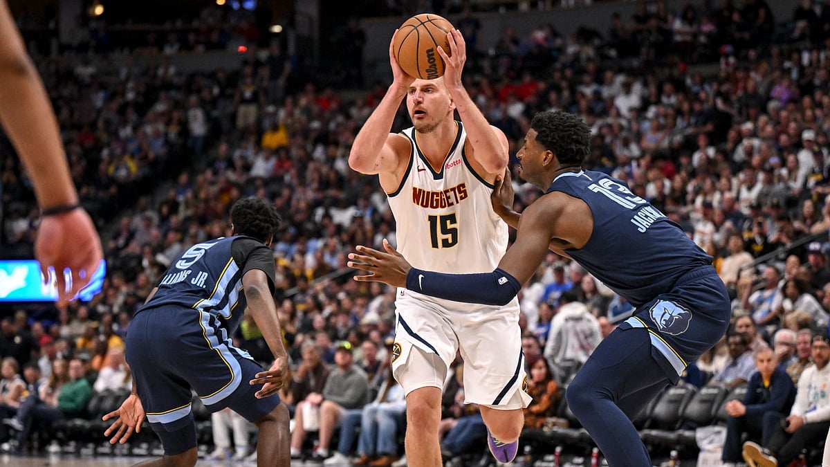 Nikola Jokic (15) of the Denver Nuggets passes as Vince Williams Jr. (5) and Jaren Jackson Jr. (13) of the Memphis Grizzlies defend during the third quarter at Ball Arena in Denver, Colorado on Friday, April 11, 2025.