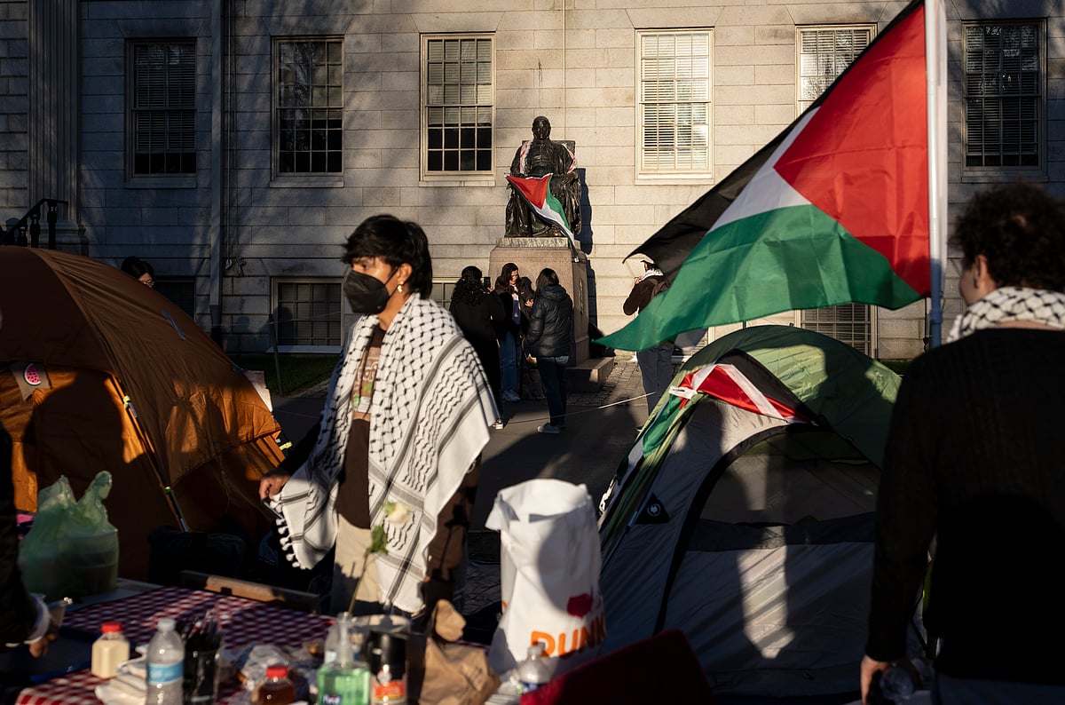 AP Photo/Ben Curtis : A student protester stands in front of the statue of John Harvard, the first major benefactor of Harvard College, draped in the Palestinian flag, at an encampment of students protesting against the war in Gaza, at Harvard University in Cambridge, Mass., April 25, 2024. 