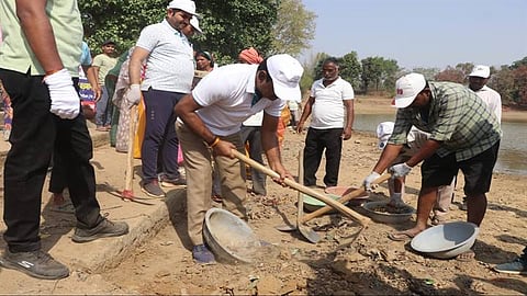 Conservation activists removing slit from pond bank