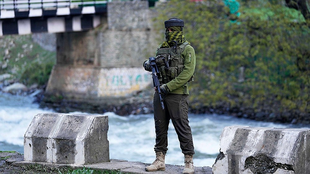  | Photo: AP/Dar Yasin : An Indian security officer stands guard by the roadside in Pahalgam a day after militants indiscriminately opened fire on tourists near the town.