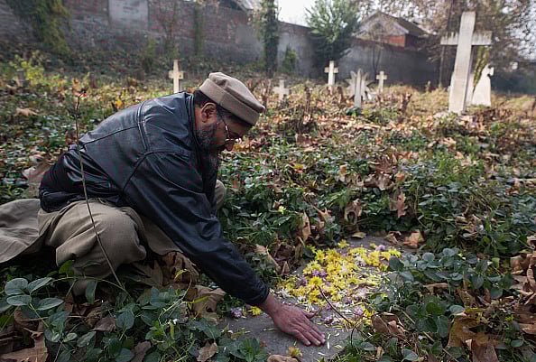 Yawar Nazir/Getty Images : SRINAGAR, KASHMIR- NOVEMBER 22: A Kashmiri Muslim man scatters flowers on the grave as he pays homage to Robert Thorpe, on his 145th death anniversary at a Christian cemetery on November 22, 2013 Srinagar, the summer capital of Indian administered Kashmir, India. Robert Thorpes father Colonel E Thorpe married a Kashmiri woman in 1833. In 1865, a young Robert visited Kashmir and wrote extensively about the miserable plight of Kashmiri Muslims under the autocratic Dogra rule in publications like Friends of India. His posthumously-published book, 'Cashmere Misgovernment' is one of the "most authentic account of unpaid forced-labour Kashmir people were subjected to under the autocratic rule and other forms of mistreatment," according to one Kashmiri historian. Although deported from Kashmir by a rattled Dogra administration, Thorpe covertly returned to Kashmir but was found dead on a hill under mysterious conditions.