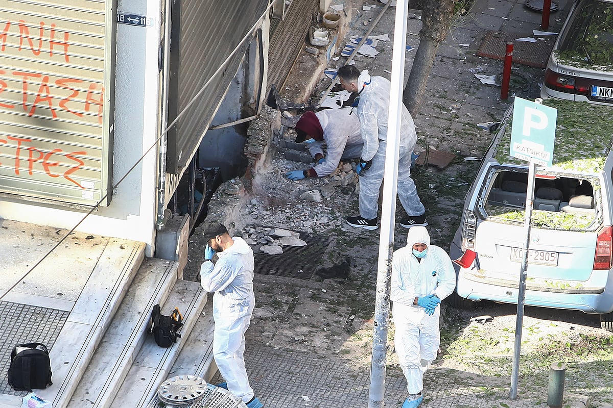 AP Photo/Giannis Papanikos : Greek police forensic experts search the spot where a 38-year-old woman was killed early Saturday when a bomb she was carrying exploded in her hands, local police said, in Thessaloniki, northern Greece, May 3, 2025. 