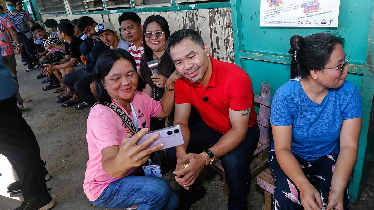 Wendell Alinea/Team Pacquiao via AP : In this photo provided by Team Pacquiao, Filipino boxing hero and former senator Manny Pacquiao has his picture taken with a voter as he arrives to cast his vote at Kiamba Central Elementary School in Kiamba, Sarangani province, southern Philippines on May 12, 2025.