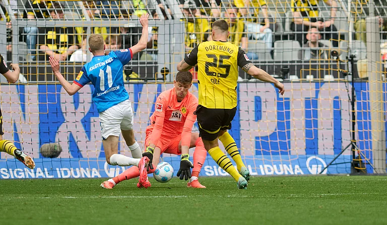 Dortmund goalkeeper Gregor Kobel, center, and Niklas Suele in action against Kiel's Alexander Bernhardsson during the German Bundesliga soccer match between Borussia Dortmund and Holstein Kiel at Signal Iduna Park in Dortmund, Germany. - Bernd Thissen/dpa via AP