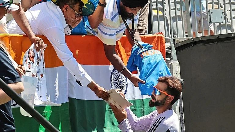 India's Virat Kohli autographs a book for a fan. - File