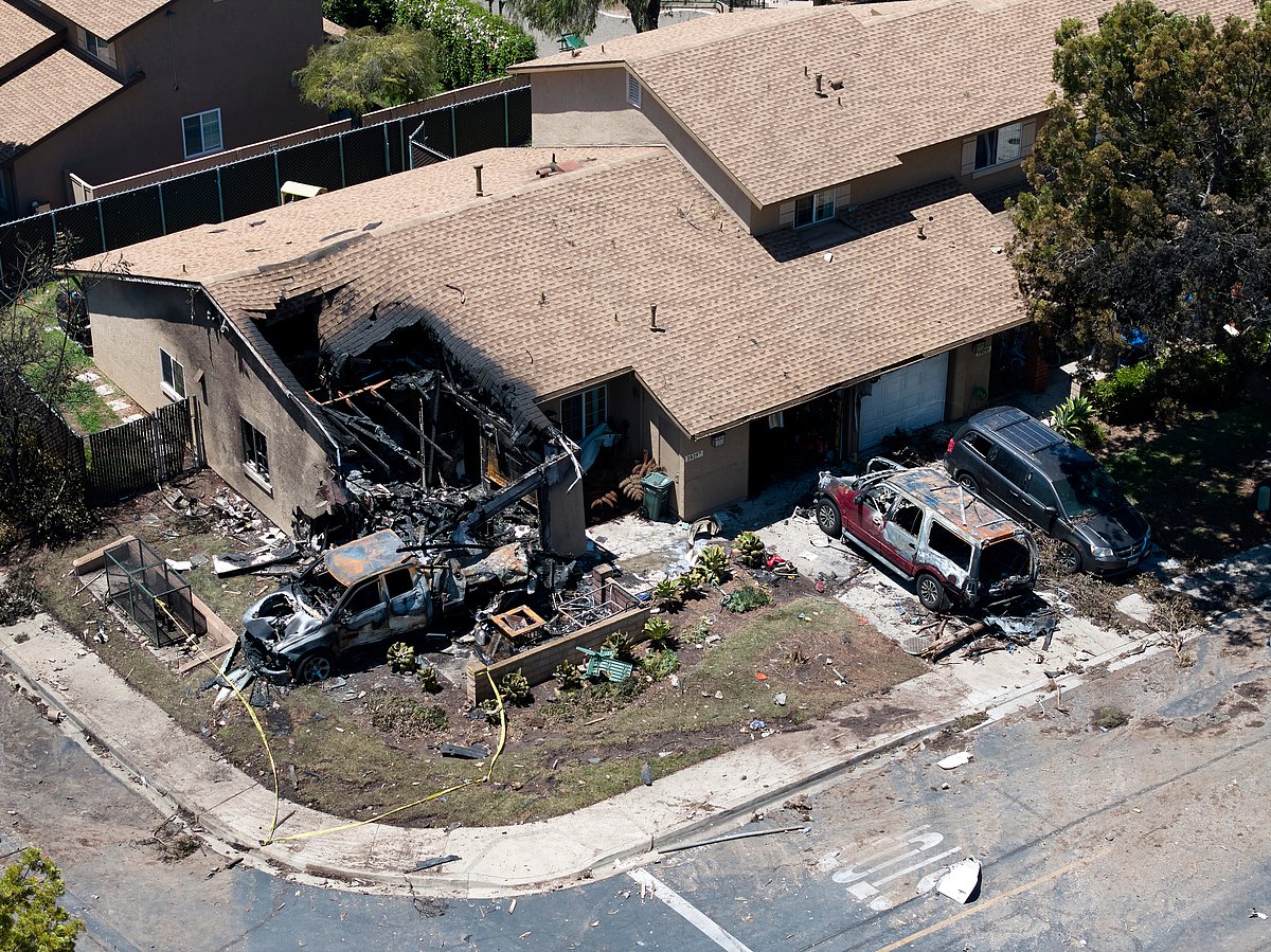AP Photo/William Liang : Debris covers the ground after a small plane crashed into a San Diego neighborhood, setting homes and cars on fire and forcing evacuations early Thursday, May 22, 2025. 