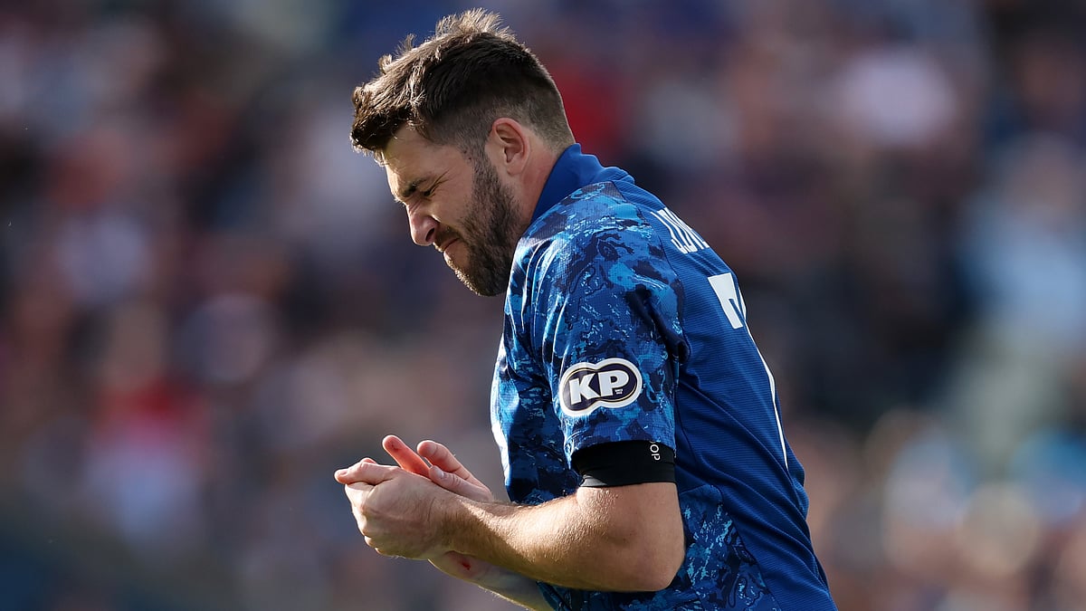 Jamie Overton grimaces as he runs off the field for treatment after injuring his hand attempting to stop the ball off his own bowling.