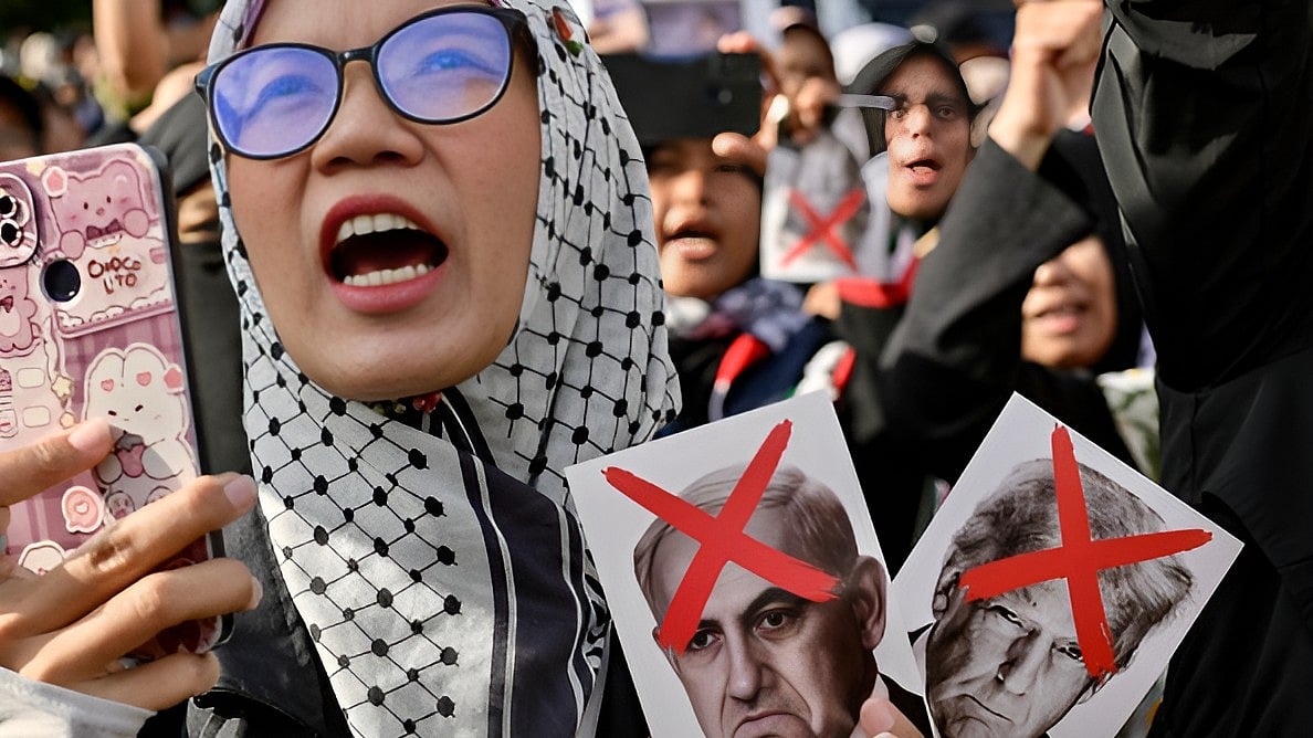 Getty Images : Woman displays crossed-out photos of US President Donald Trump and Israeli leader Benjamin Netanyahu while joining hundreds of others in a demonstration in front of the US embassy protesting against the Israeli attack on Gaza