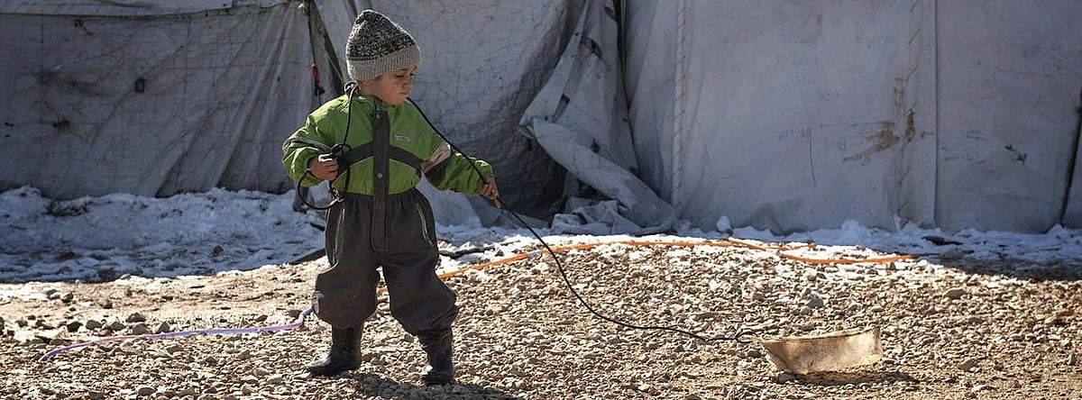 | Photo- UNICEF/Romenzi : A child plays with a homemadesled made from an empty container and a length of cable, in Roj Camp, northeast Syria.