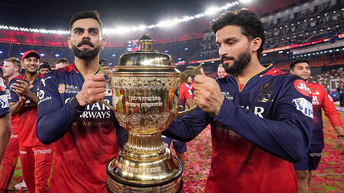 | Photo: PTI : Royal Challengers Bengaluru captain Rajat Patidar (right) and Virat Kohli hold the Indian Premier League 2025 trophy during the team's victory lap at the Narendra Modi Stadium in Ahmedabad.