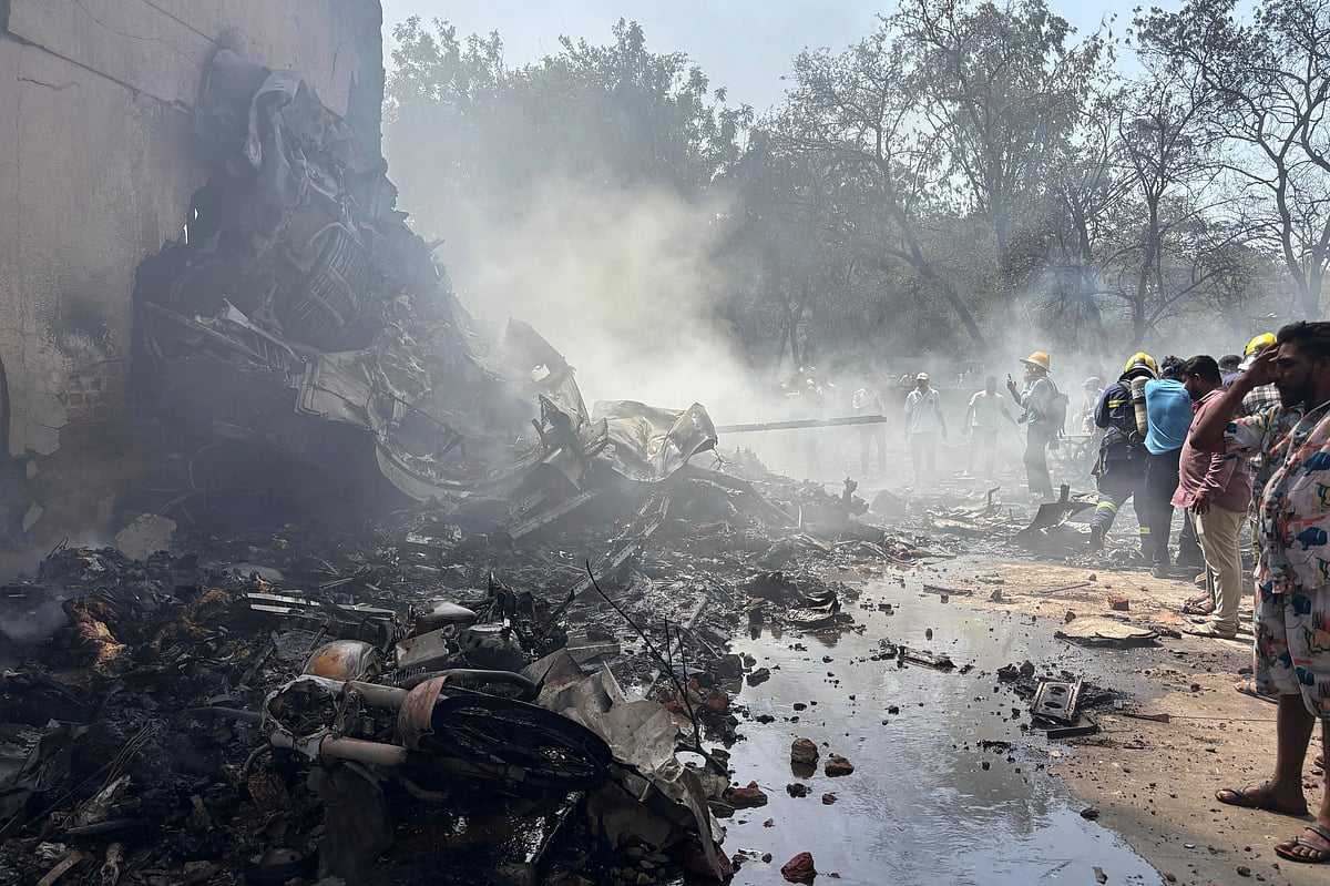 AP : People standing around debris at the airplane crash site in Ahmedabad