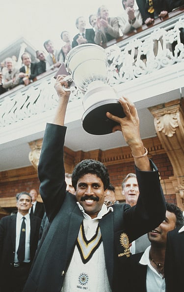 LONDON, UNITED KINGDOM - JUNE 25: India captain Kapil Dev lifts the trophy on the balcony of the pavillion as Sunil Gavaskar (obscured right) looks on after the 1983 Prudential World Cup Final victory against West Indies at Lords on June 25, 1983 in London, England.