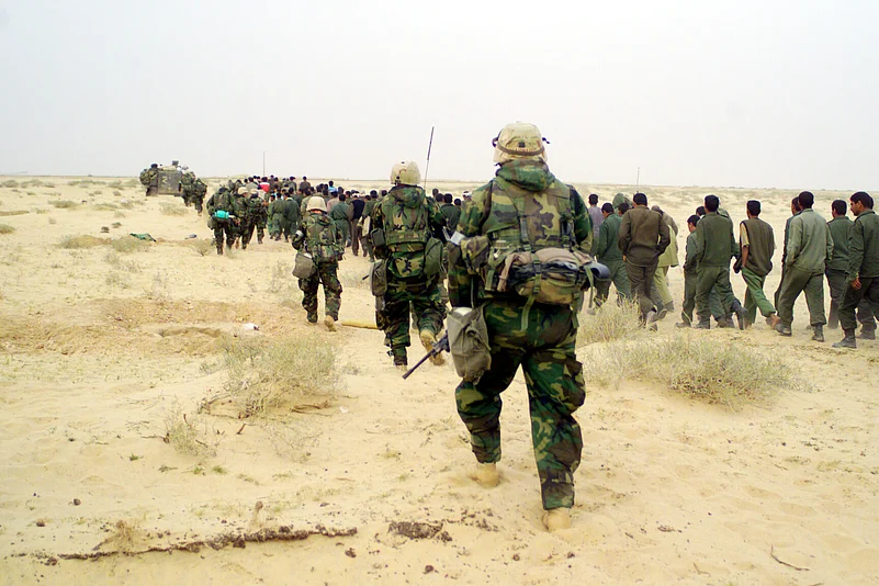 US Marines escort captured enemy prisoners to a holding area in the desert of Iraq