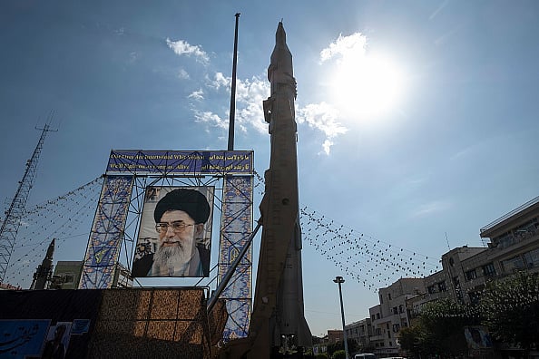 Photo by Morteza Nikoubazl/NurPhoto via Getty Images : An Iranian Sejjil ballistic missile pictured next to the portrait of Ayatollah Ali Khamenei in Tehran