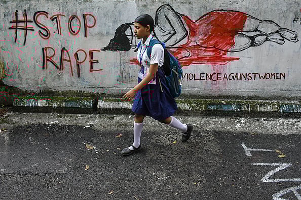 Getty Image : A school girl walks past wall graffiti painted in protest against the rape