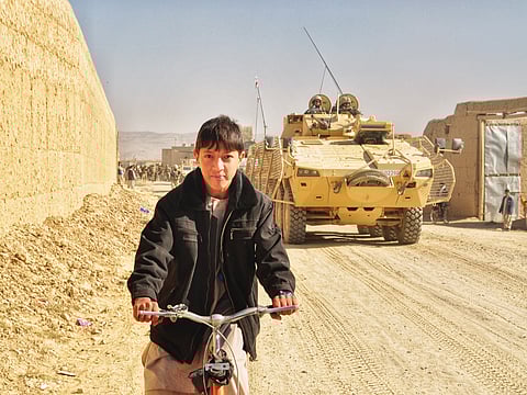 A boy riding a bicycle amidst Afghan War