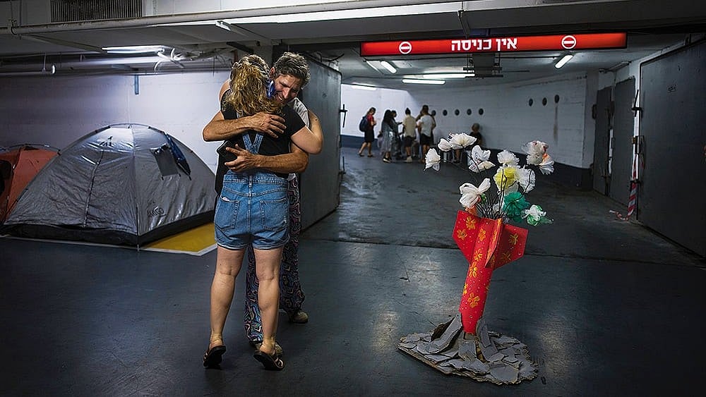 | Photo: AP : Fragile Truth: People hug in an underground parking garage to protect themselves from possible Iranian missile attacks in Tel Aviv, Israel, on June 23, 2025