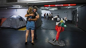 | Photo: AP : Fragile Truth: People hug in an underground parking garage to protect themselves from possible Iranian missile attacks in Tel Aviv, Israel, on June 23, 2025
