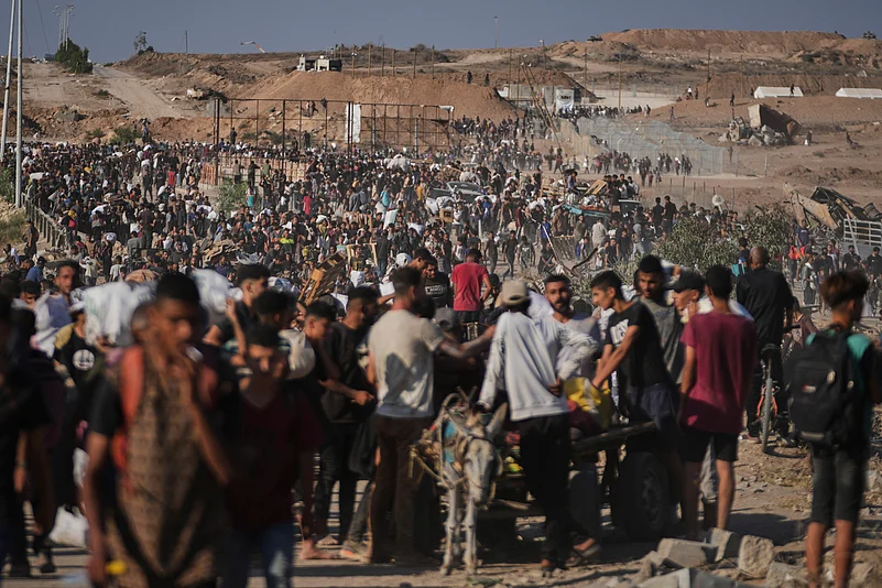 Palestinians carry humanitarian aid packages near the GHF distribution center