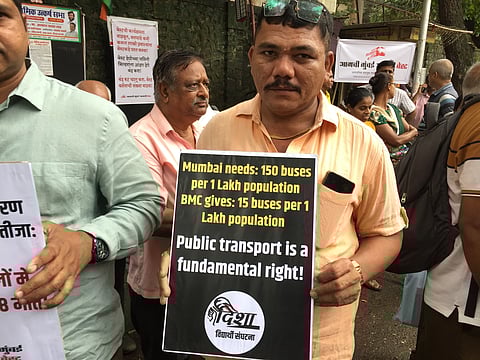 A man holding a poster at the protest side near Vadala Bus Depot.