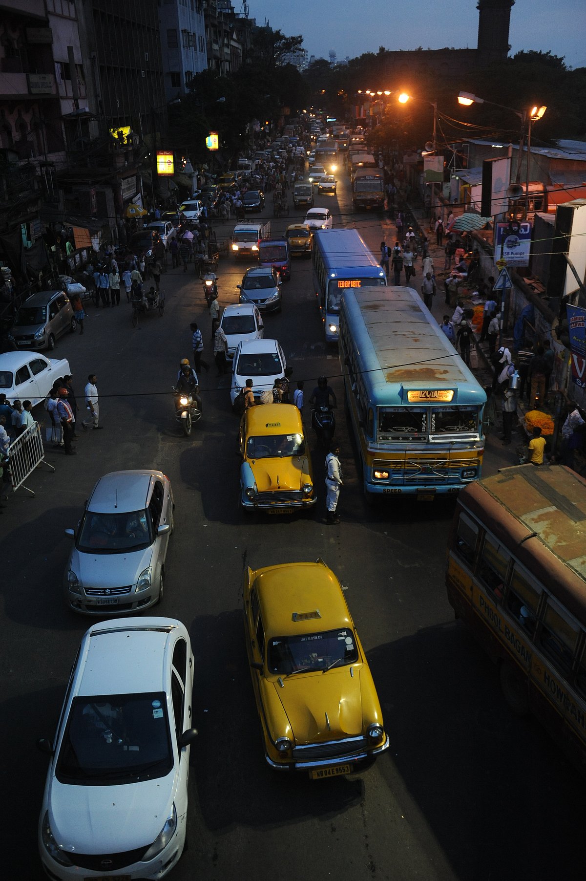 Yellow taxi plying on Kolkata city Burra Bazar area with the other vehicles in the evening time. 