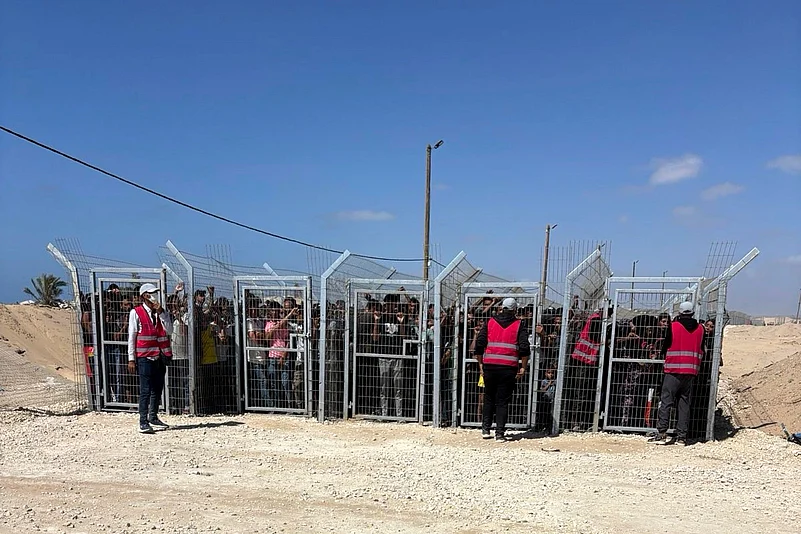 Palestinians behind gates before entering a food distribution site operated by the GHF